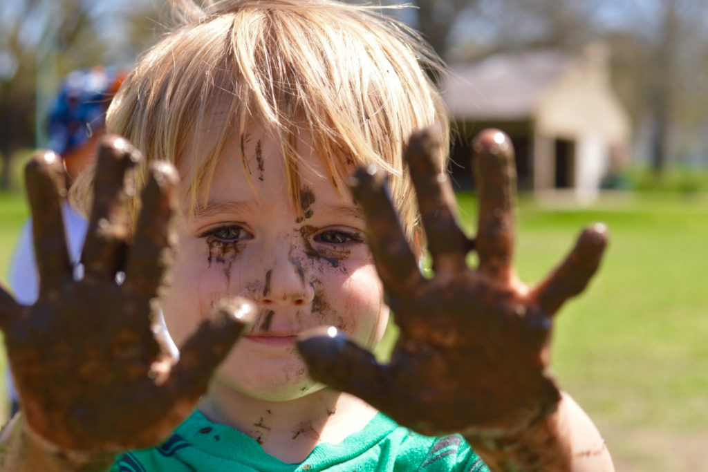 A boy with muddy hands.