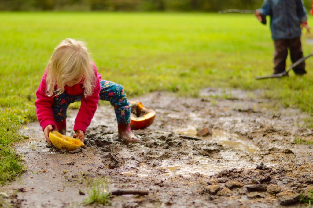 A girl playing in mud.