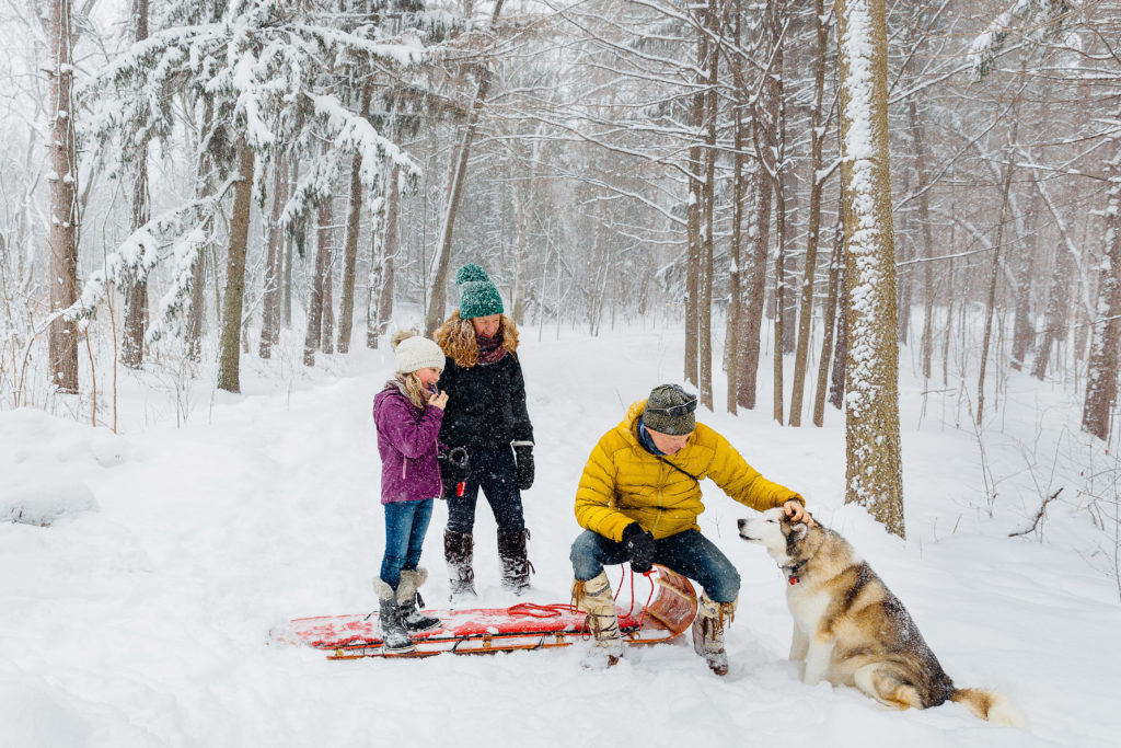 A family with their dog in the snowy woods.