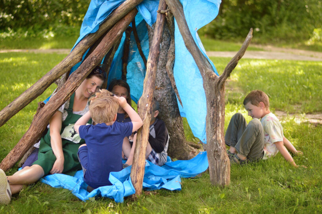 A woman and kids underneath a shelter they built.