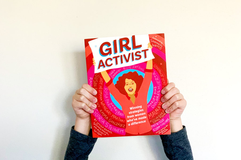 A girl holding up the Girl Activist book.