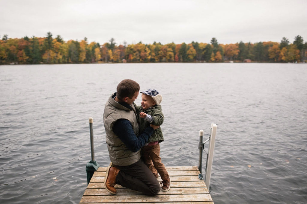 A father and son on the dock by a lake in fall.