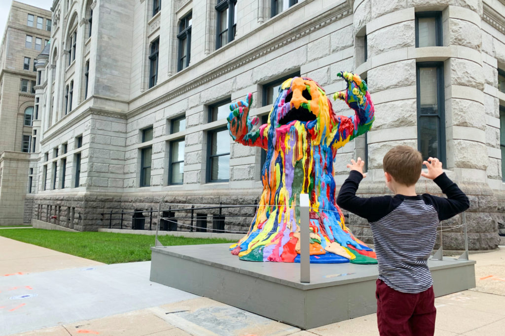 A boy greets Blob Monster, a colorful sculpture on Wisconsin Avenue in Milwaukee.
