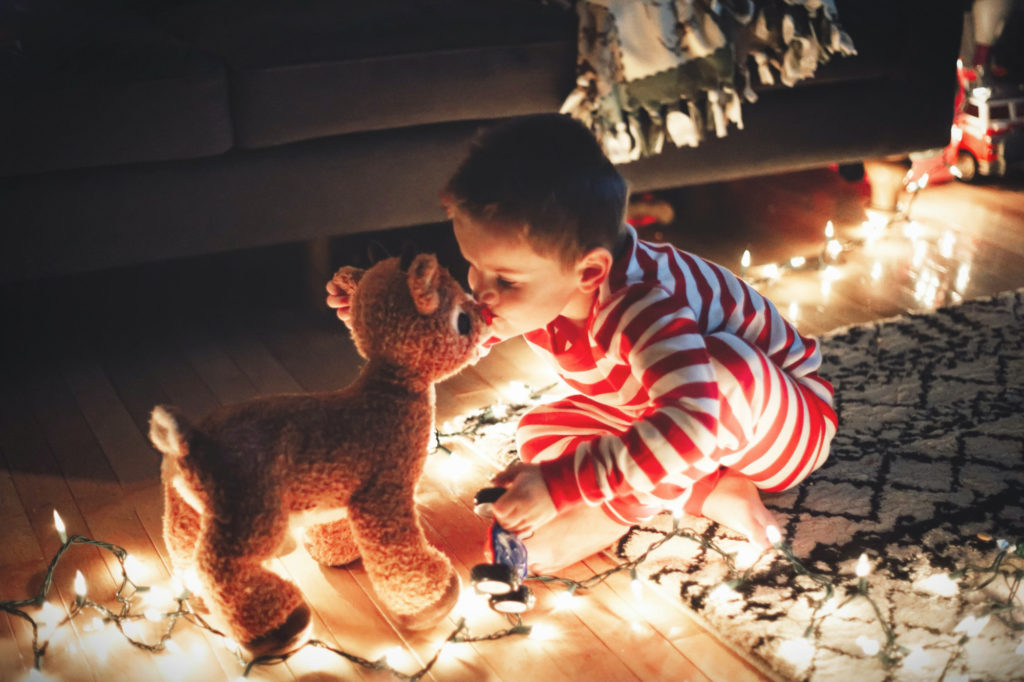 A boy kisses a stuffed reindeer. 