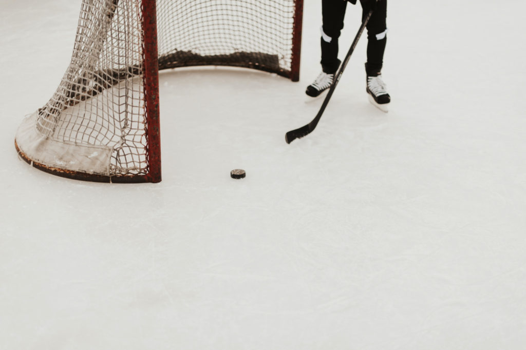A hockey player stands by a hockey net.