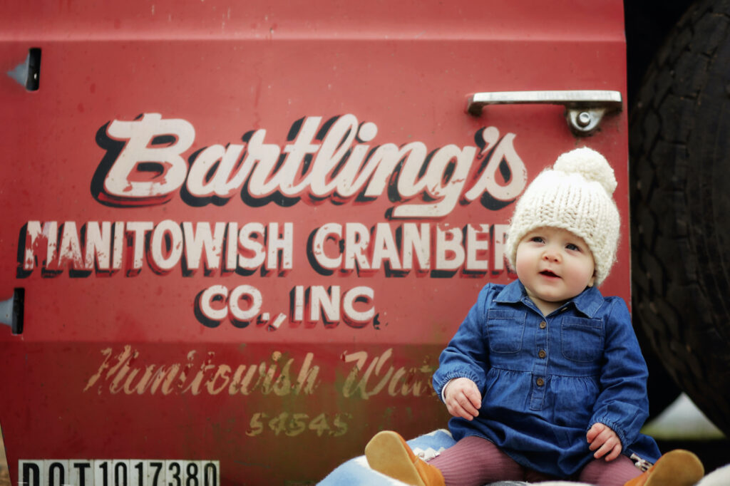 Baby Lucy sits in front of her family's cranberry truck.