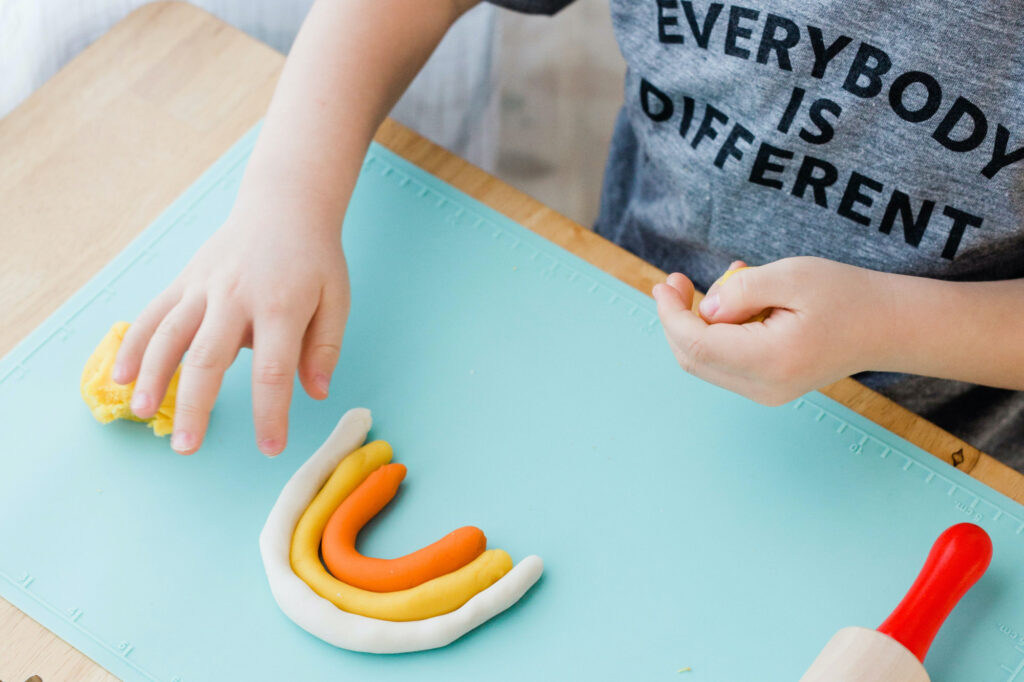 A boy rolls ZDough play dough into a colorful rainbow.