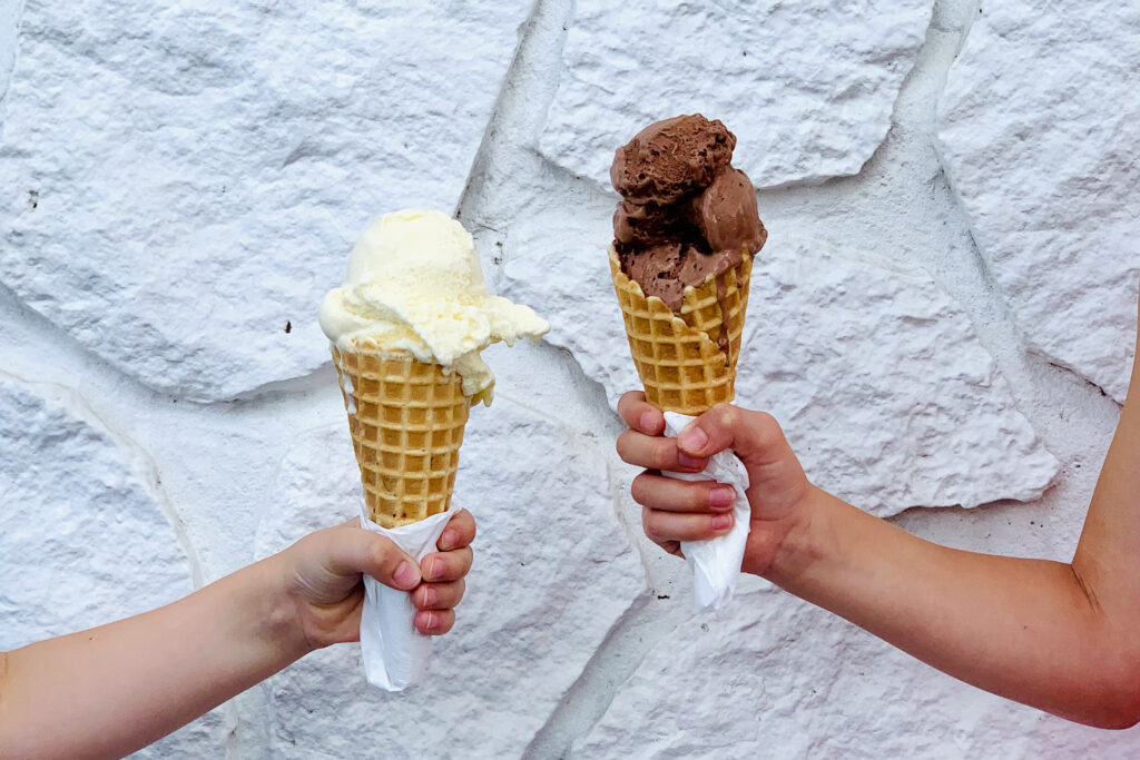 Two kids hold giant cones of frozen custard.