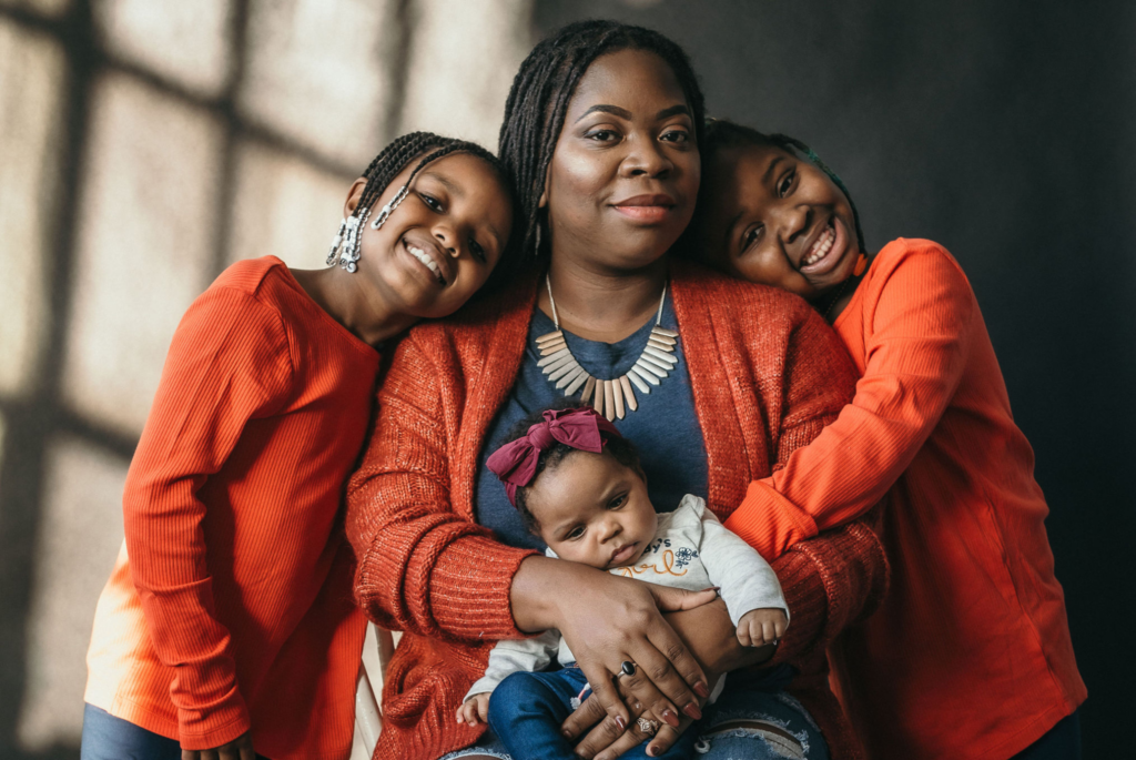 Symphony Zawadi sits with her baby and two daughters.