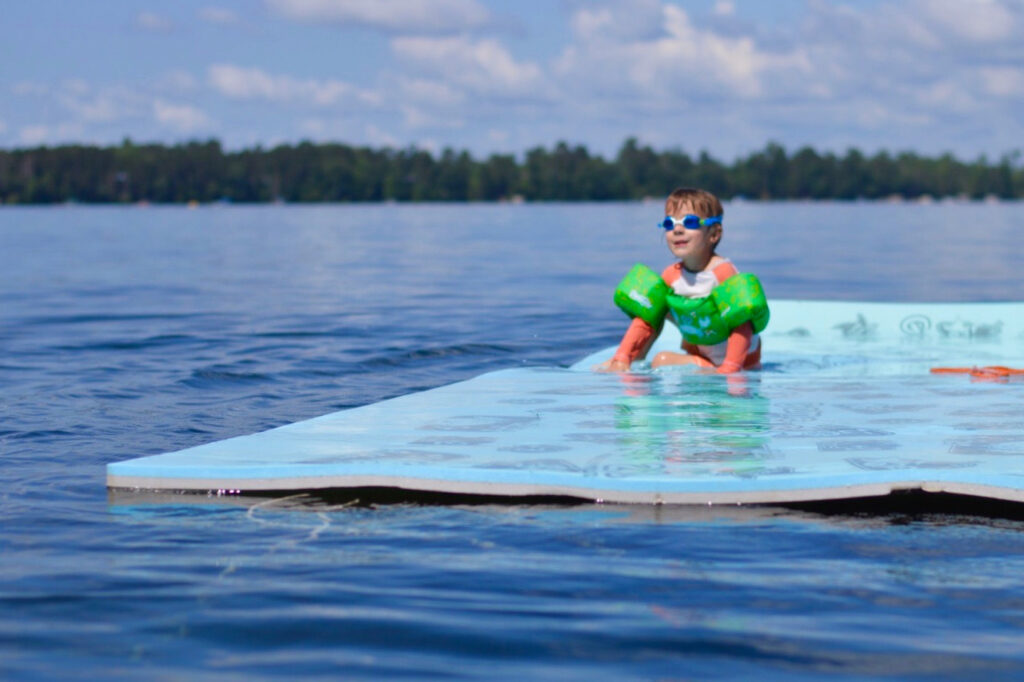 A boy sits on a floating pad on a Wisconsin lake.