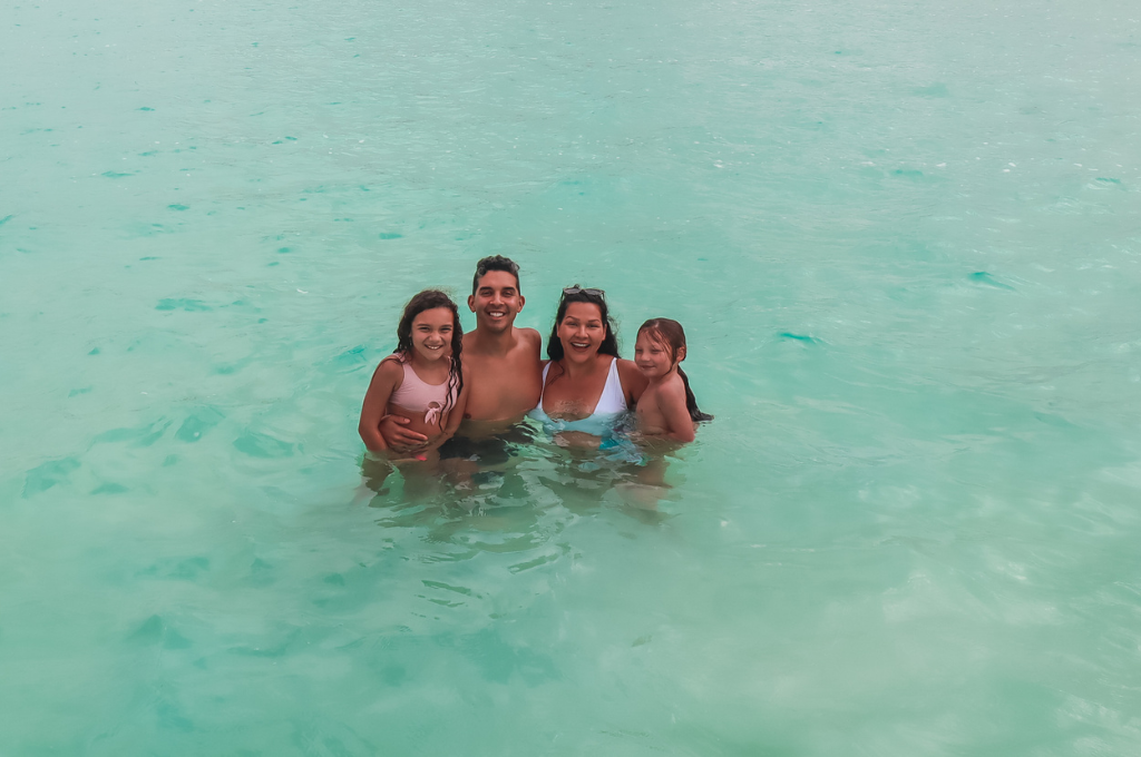 The Salas family standing in turquoise ocean water.